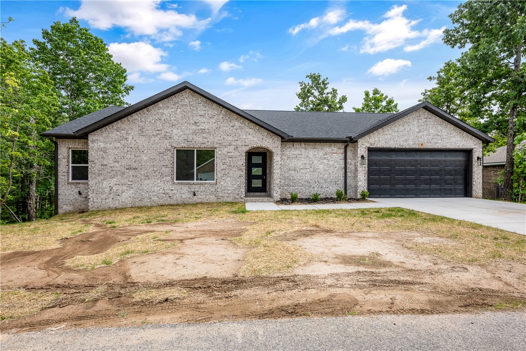 Just completed and move-in ready, this beautiful new construction is located in the southwest area of Bella Vista. The relatively flat yard is a rare find in Bella Vista, offering more functional outdoor space. Enjoy the peaceful setting from the large covered deck, perfect for relaxing or entertaining. This 3-bedroom, 2-bath home includes an oversized 2-car garage and an attractive exterior with an all-brick front and low-maintenance vinyl siding on the sides and back. Inside, the open living area showcases vaulted ceilings with decorative beams, creating a warm and inviting atmosphere. LVP flooring runs throughout the home, with tile flooring in the primary bathroom. The kitchen is beautifully finished with granite countertops, a classic white subway tile backsplash, and plenty of workspace for cooking and gathering. The primary suite offers a large walk-in closet along with a spacious bathroom featuring dual vanities, a fiberglass shower, relaxing soaker tub, and separate toilet area for added privacy.
