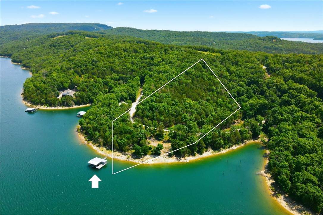 Exceptional opportunity to own 5.43 acres of lakefront property with lake views and a private 2-slip dock in Fords Creek on Beaver Lake!  Finally checking every box on the lake buyer wish list!  Rare, low lying property line extends into the water allowing for a home site not only close to the shoreline but also offering unobstructed water views. Peaceful and secluded, this parcel is rich with possibility...covenants permit up to two residences per lot or parcel division (no less than 2 acres) creating possibilities for a private estate, multi-home retreat, family compound or investment opportunity. Whether seeking lake frontage, lake views, acreage, or a private dock, this property delivers the complete package! The two boat slips are 10'x30' and the swim deck is 8'x36'. Well and septic required.