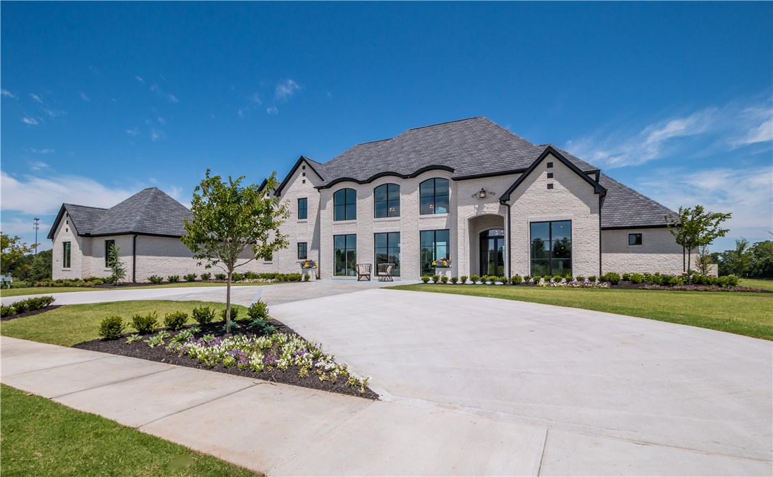 Set majestically on a perfect 0.96 acre, this estate offers an incredible location that affords both serenity and convenience. Beautifully proportioned for entertaining, the interiors were thoughtfully designed with exquisite fixtures & finishes. This home features a marble 2-sided fireplace, designer chandeliers, stunning paneled walls & a custom floating spiral staircase, white oak hardwood flooring, Windsor wood clad windows, vaulted ceilings, designer paint palette, 3 fireplaces, Wolf & SubZero appliances, marble & granite countertops & oversized picture windows filling the home with natural light. Step outside to enjoy the spacious wrap around covered veranda with a sleek outdoor glass rock fireplace & grilling kitchen! Bentonville schools.