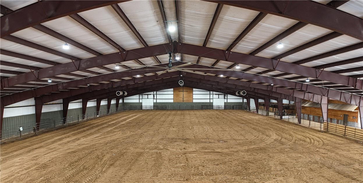 Exceptional equestrian property featuring a 49,466 SF enclosed horse arena situated on 25 acres of lush pastureland! Arena has a metal exterior, sand/dirt mix footing, LED lighting, fully insulated, commercial-grade ventilation, heating, and Big Ass Fans for year-round comfort & performance. Stunning glass overhead doors provide natural light & easy access. Interior amenities include trailer parking, a concrete-floored viewing area with drink ledge, unique “jailhouse” and ticket window, tack room, ample storage, & 6 Priefert horse stalls. On-site living quarters with HVAC offer convenience for owners or staff. The land is pipe fenced & enhanced by a spring-fed pond, natural spring, & frost-free hydrants & waterers in the field. A rare, turnkey facility ideal for training, events, or private equestrian use. Close to XNA airport & the new 612 highway!