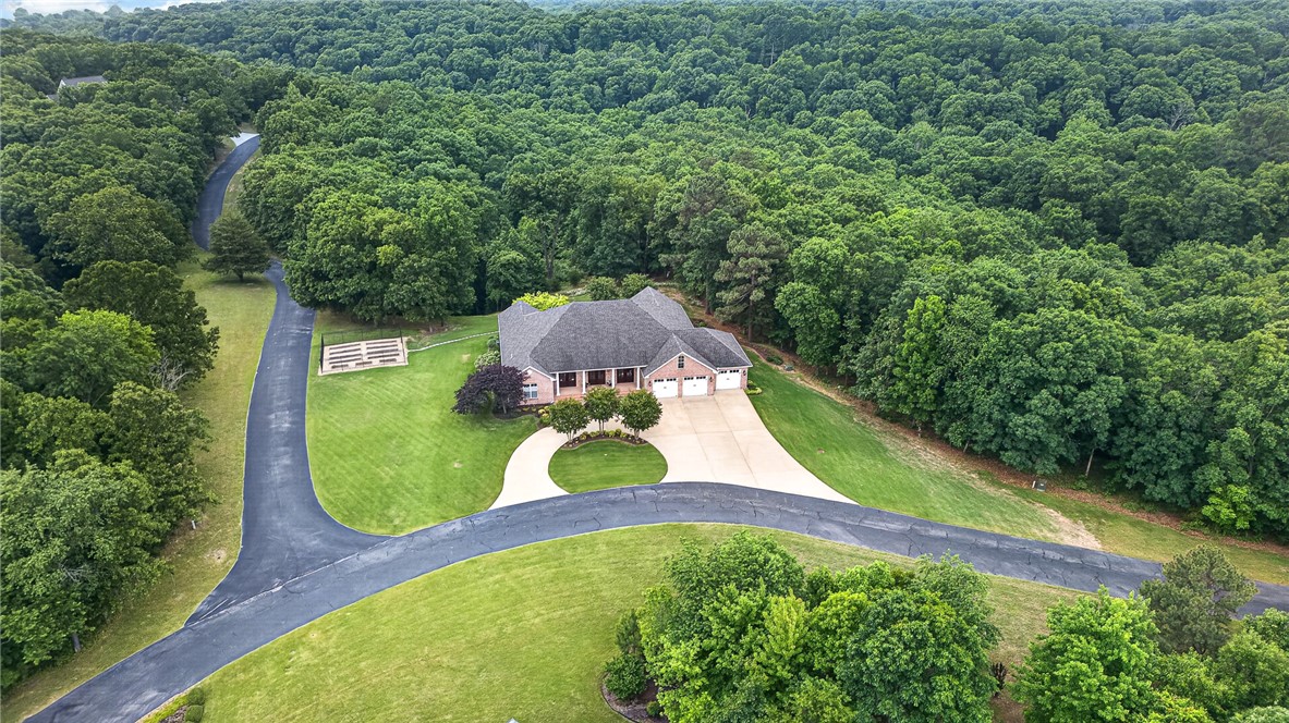 Welcome to this stunning custom-built Southern masterpiece nestled on 4.61 park-like acres in the sought-after Summerwood Subdivision with a beautiful private stone bridge entrance. Gorgeous curb appeal showcases a stately covered front porch with columns and multiple double doors inviting you into this timeless Southern charmer. Just off the foyer are an elegant formal dining room with built-ins and a private office, both opening to the front porch. The inviting living room features a fireplace flanked by built-ins and a wall of windows leading to a sprawling covered back deck overlooking peaceful wooded views.The chef’s kitchen impresses with double ovens, gas cooktop, island, pantry, and ceiling-height cabinetry. Luxurious primary suite with spa-like bath, large tiled shower, soaking tub, and boutique-style closet. Property features multi-level deck/patio with firepit, gas grill, gardens, lush grounds, 5 trails, and a private nature wonderland beyond compare! Incredible storage space & whole-house generator!