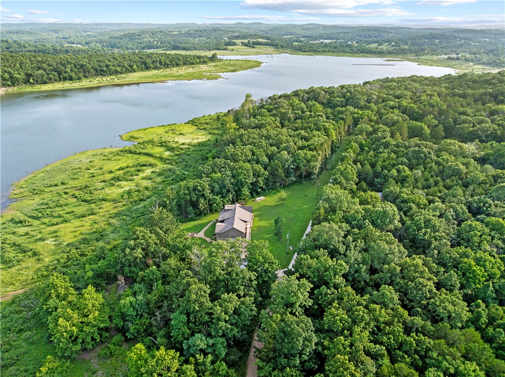 One of Bull Shoals Lake's most desirable properties, this custom retreat sits on approximately 5.11± acres surrounded by Corps of Engineers land on three sides, offering exceptional privacy, year-round water views, and one of the rare few gentle, walkable slopes to the shoreline. When Bull Shoals Lake is at capacity, the water extends to within approximately 50 yards of the backyard. The 2,810± SF main home offers 4 bedrooms and 2.5 baths, featuring Brazilian granite countertops, custom maple cabinetry, Southern Michigan Swamp Oak flooring, a wood-burning stove, and an upstairs bedroom with a private balcony overlooking the water. A detached 2-car garage/shop with a beautifully finished cedar interior provides exceptional space for vehicles, hobbies, or storage. The 1,100± SF guest home offers 1 bedroom and 1.5 baths, ideal for guests, multi-generational living, or rental potential. Conveniently located just outside Lead Hill, only 25 minutes from Harrison and 45 minutes from Branson.