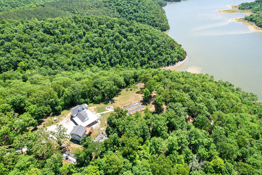 Experience unparalleled lakeside living in this magnificent waterfront estate! Custom-built masterpiece showcases quality craftmanship and timeless design throughout. Elegant finishes and thoughtfully designed layout boasts glorious natural light throughout. Nestled on 22.38 acres of serene land provides unmatched privacy and breathtaking views of the water from all rooms. Modern HVAC paired w/ a classic Vermont Castings wood stove. Established berry plants, fruit trees, fenced vegetable garden and a greenhouse with 2500 gallon water collection system. 500 feet of private beach allows your days to be spent fishing, kayaking, swimming, or beachcombing. Many hiking trails to explore, or relax on the expansive covered patios designed for seamless outdoor entertaining. 24x30 detached shop (110V) plus a garage features a 220V workshop area. Private 1-bedroom studio guest house has kitchen and stunning lake views above the garage that is perfect for visitors. Indulge in pristine lake living that literally has it all!