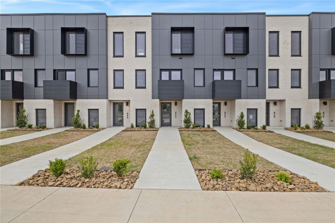 Enjoy the best of downtown Bentonville living in this luxury Lightbox townhome—designed for ones who want walkability, style, and smart design. Located just one block from the new Walmart Home Office campus and directly across from 8th Street Market, this North Light residence offers expansive northern views, including the Momentary. The architecturally striking design allows natural light to pour in from third-floor clerestory windows down through the open stairwell to the main living level, creating a bright, calm, and modern feel throughout. The kitchen blends form and function with a European Bosch appliance package, induction range, white oak cabinetry, and bold quartz countertops. Across the catwalk, the living area is framed by oversized windows—perfect for relaxing or entertaining with a view. Upstairs, two private bedroom suites each feature their own bath, offering flexibility for guests, work-from-home space, or a refined second-home lifestyle—all just steps from Bentonville’s dining, arts, and trails.