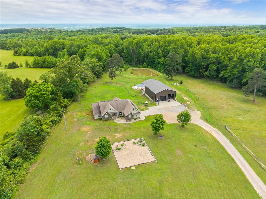 This beautiful 4-bedroom, 3-bath home situated on 5.05 private acres just North of Alma really checks all the boxes! Inside, you’ll find hardwood flooring, quartz countertops, a gas log fireplace, and a desirable split-bedroom floor plan. The spacious primary suite features two walk-in closets, dual vanities, and a custom tile shower. Fridge, Washer & Dryer all convey. Enjoy outdoor living year-round with both covered front and back porches, plus the peace of mind of two storm shelters inside the two-car garage. The solar panels help keep your monthly utility costs at a fraction of what you’d expect. The impressive 40x50 shop is custom finished and offers versatile space perfect for vehicle storage while also doubling as a pool house complete with a full kitchen and bathroom. Step outside to a 20x40 covered patio overlooking the in-ground saltwater pool, ideal for entertaining. The acreage is mostly open and includes a pond and plenty of room for animals. Privacy and country living at its best!
