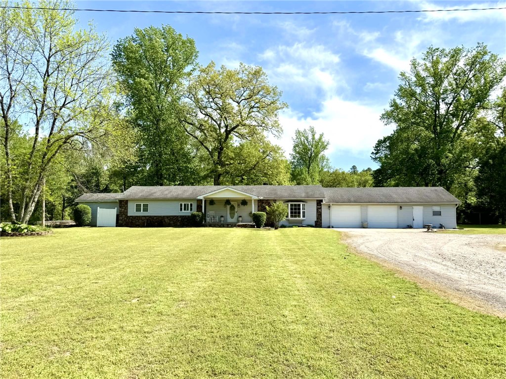 Discover country living at its best with this charming 3-bedroom, 2-bath home located on Broomfield Rd just outside of Dover, with fiber-optic high speed internet available. The main living room features a stunning rock fireplace built from stones found right on the property, adding a touch of character. A second living area opens to a bright sunroom, perfect for relaxing or entertaining. The kitchen offers ample space with a pantry, double oven, and electric cooktop, while the dining area provides a welcoming spot for family meals. Outside, you’ll find a 2-car garage with an attached workshop, a metal detached carport, and an additional workshop for all your projects or storage needs. The property also includes a storm shelter, a creek with a bridge leading to wooded acreage, and an old barn—offering endless potential for outdoor enjoyment.