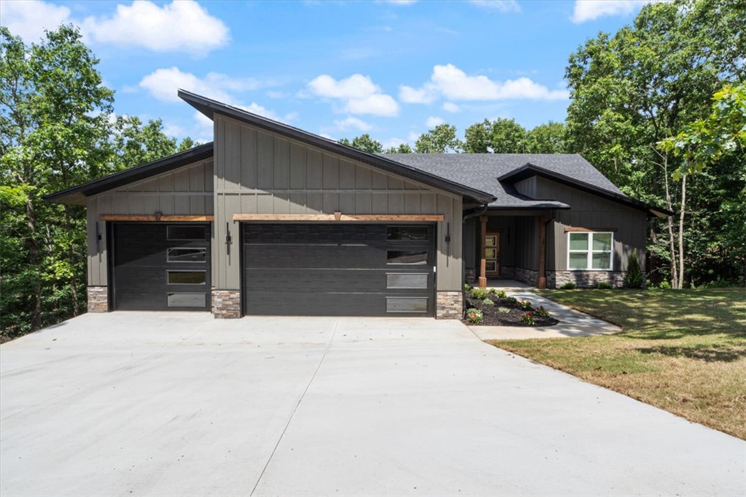 Custom-built contemporary craftsmanship meets everyday luxury in this stunning 3BR + Office, 2BA home featuring 1,929 SF of thoughtfully designed living space plus an oversized 777 SF insulated, EV-ready 3-car garage. Premium finishes include soaring ceilings, engineered hardwood floors, white oak beams, quartzite waterfall island with matching backsplash, custom shaker cabinetry, hidden walk-in pantry, under-cabinet lighting, designer electric fireplace, dedicated office with glass doors, and a spa-inspired primary suite with freestanding soaking tub and tiled shower. Built for efficiency and longevity with Low-E argon windows, Lennox HVAC, Starlink wired, reinforced crawlspace, architectural shingles, cedar accents, and a spacious deck overlooking the backyard. Crafted by a respected Northwest Arkansas builder with more than 25 years of experience, this home delivers exceptional quality rarely found at this price point. Located near Scotsdale Golf Course, Loch Lomond Recreation Area, and I49 for easy commute.