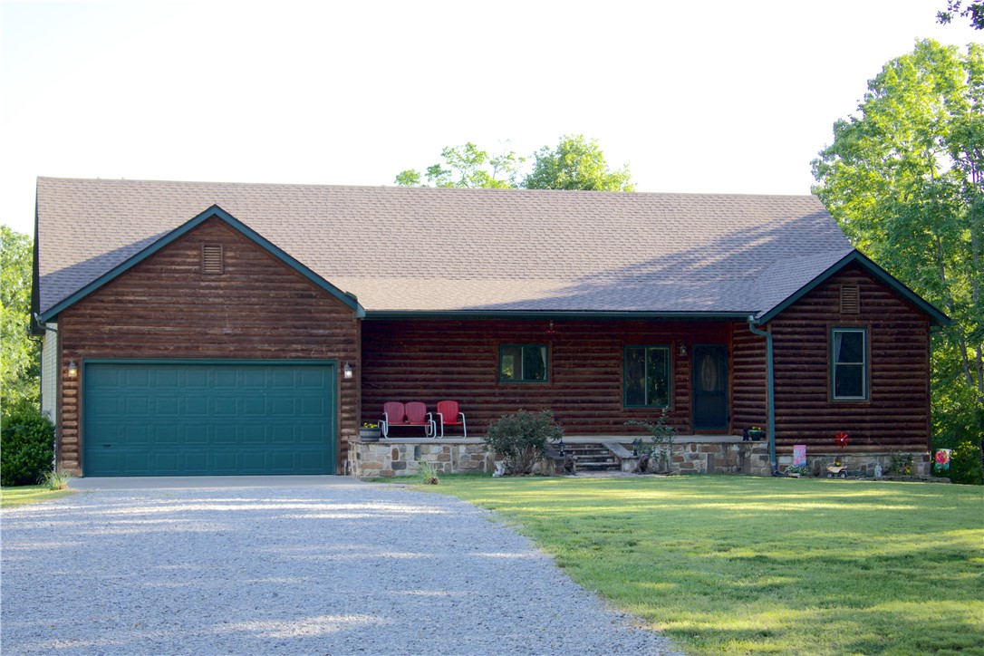 Welcome to country living just southeast of Elkins! This 4,076 +/- sq ft home sits on 5.32 +/- acres and offers room to spread out. Built on a concrete slab, the home features two nearly mirrored levels which is ideal for multi-generational living or hosting friends and family! With 5 bedrooms and 3 full baths, each level includes its own living area and kitchen space. The upper level offers natural hardwood floors, a wood-burning fireplace, and a well-appointed kitchen with granite countertops, wood cabinetry, stainless sink, and  large pantry. The master bedroom with ensuite bath, plus two bedrooms and another full bath are also on this level. Downstairs includes a second living area, 2 bedrooms, 1 bath, propane fireplace, and a storage room with potential to be a 6th bedroom or office. Additional features include a built-in storm shelter under the stairwell. In addition, this home has over 800 sq ft of covered porch/deck space, attached 2-car garage, and a 40’ x 30’ shop with ample outlets and storage!