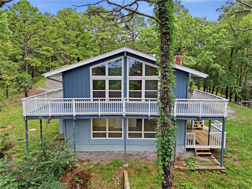 Updated home on 2.21 acres just outside city limits of Eureka Springs (short term rentals allowed).  Surrounded by nature, yet 2.4 miles and a 10 min drive to Downtown Eureka Springs (Basin Spring Park).  Or utilize Eureka Springs transit system and hop on the trolley via trolley stop #37 (4 min walk).  Extensive improvements completed in 2024 (see attachments for detailed list).  Improvements were completed honoring the mid-century modern style of the home. View the treetops from floor to ceiling windows in the living room.  Living room has wood beam vaulted ceilings, built-in bookcase w/limestone top and designer embossed painted wallpaper. Large primary suite and guest bedroom with cedar lined closets located on main level. Bathrooms have been updated while maintaining mid-century modern aesthetic. Galley kitchen is equipped with SS appliances and limestone counters (sourced from local quarry). Downstairs contains a large living area, hidden bedroom, full bath, wet bar with sink, wine fridge and dishwasher.