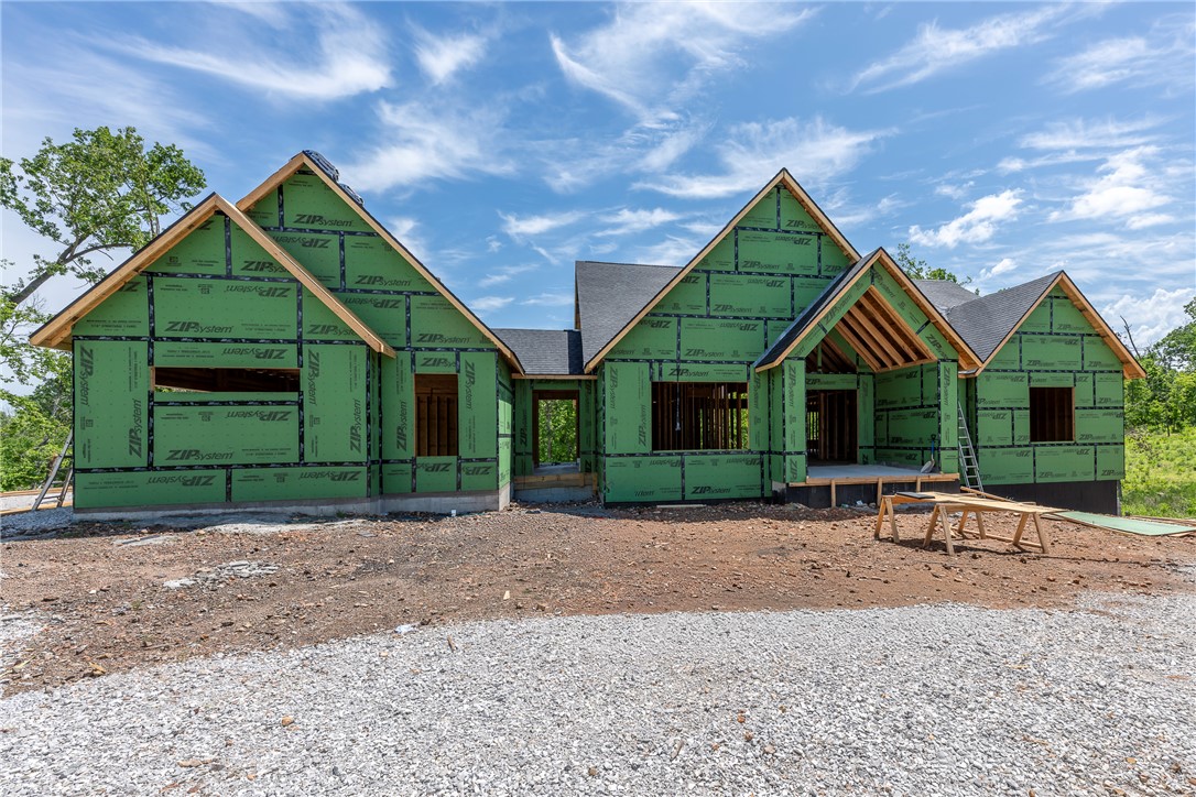 Tucked into a wooded setting just minutes from the best of Bentonville, this 6,800 sq ft luxury home on 3 acres offers the rare blend of privacy and proximity—only 1 mile to the new Walmart Campus and upcoming medical center, 2 miles to the Bentonville Square, and quick access to I-49. Vaulted ceilings draw you through the main living space to an expansive upper deck overlooking a stunning resort-style pool framed by mature trees. The kitchen is a showpiece with white oak cabinetry in a walnut stain, integrated refrigerator, 48” gas range, and a walk-in pantry built for real use. The main level features a private office, guest suite, and a serene primary retreat with a spa-inspired bath, European wet room, and direct deck access. The lower level is built for entertaining with a second kitchen, pool bath, game room, and flexible bedroom spaces—all opening to your private outdoor escape. Crafted by a 3rd generation local builder. Customize the finishes today!