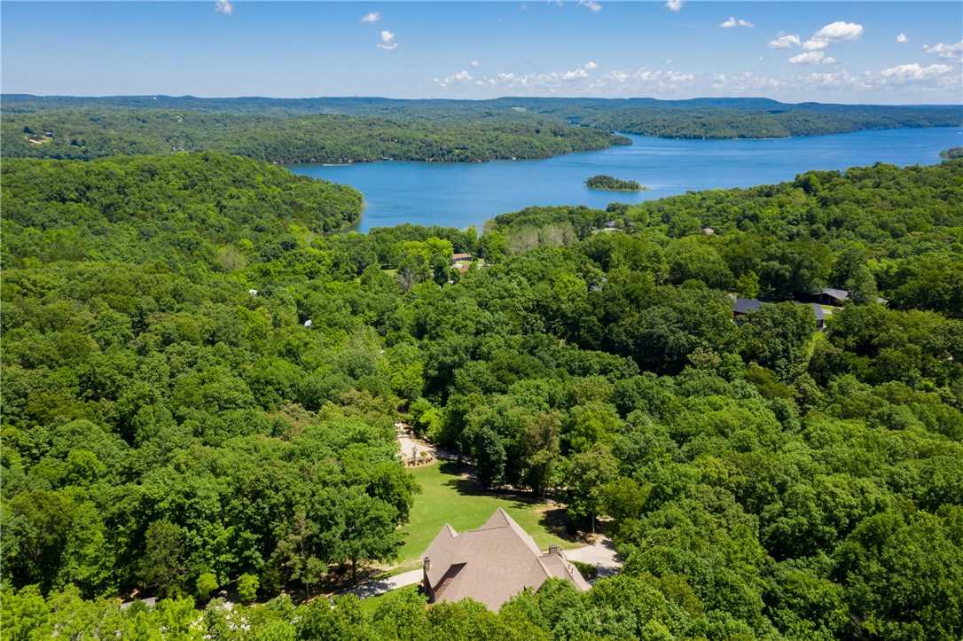 Incredible 14 acre Ozark Estate located in Northwest Arkansas overlooking beautiful Beaver Lake. Throughout the property you will find native dog wood trees, soaring oaks, wet weather creeks that create mini-waterfalls and abundant wildlife. The main home is over 4200sqft of elegance with soaring 20ft ceilings and amazing wood work. This home has multiple advantage points for you to enjoy the views including a private alfresco dining porch off the kitchen. The other great space to relax and enjoy is the screened in morning porch off the master suite with hot tub and outdoor seating under the pergola. The majority of the main house was remodeled over the last 2 years.  The property also includes a “Barn-ominium” which makes the perfect workshop or man cave. It includes a 1,000sqft of living quarters finished in a modern rustic feel with wrap around deck and screen patio area. This is true Ozark Estate located minutes from the marina, museums, restaurants and more.