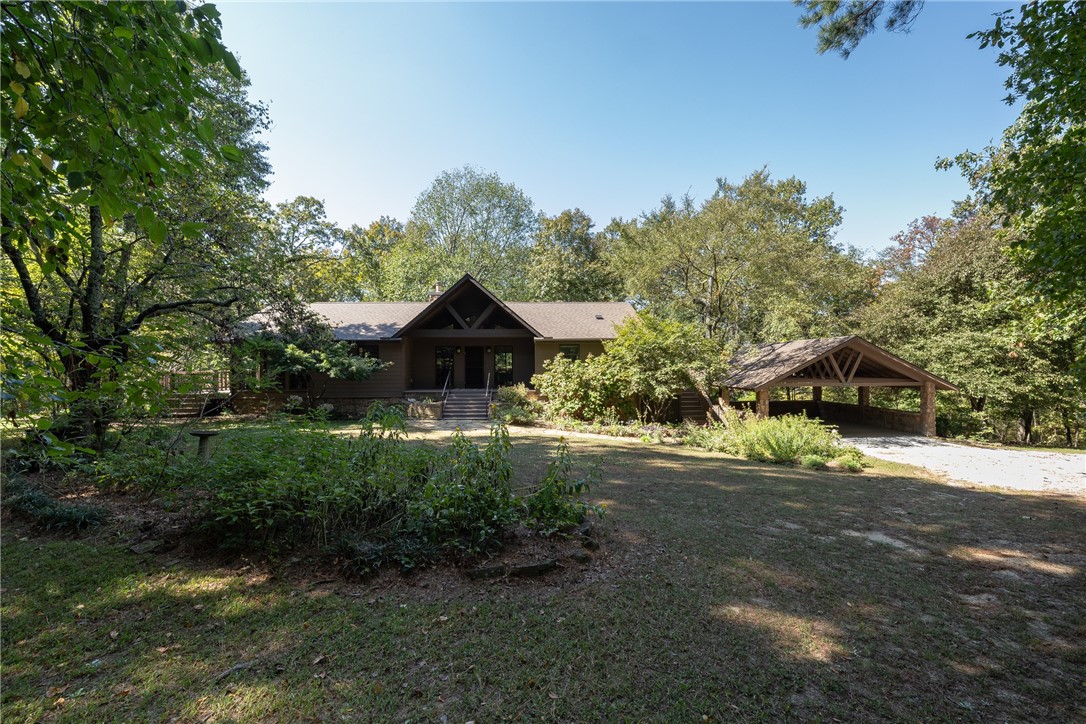 The most peaceful, serene setting with a gorgeous home situated on 8.71 acres in East Fayetteville!   3,487 heated sq ft offers 3 bedrooms, 3 full bathrooms, eat in kitchen, great room, a home office, bonus room, second living, laundry room, and a basement workshop that is heated and cooled and NOT included in the sq ft. Amenities include wood casement windows and some floor to ceiling windows, a true chef’s kitchen with a 6 burner gas cooktop, double ovens, microwave in the island, quartzite countertops, quarter sawn white oak cabinetry, spa like primary bathroom, Vaulted ceilings, a new Petra wood insert, BRAND NEW ROOF AND GUTTERS, 2 car carport, marathon HWH, tons of storage, 2 HVAC units on a maintenance contract, wrap around decking, mowing shed, 6” exterior walls, and NEW Hardy board siding in 2023. Have I mentioned that there is a SPRING FED CREEK on the property? All in Vandergriff School District. This home offers so much quality, living space, and natural light. It truly is special!