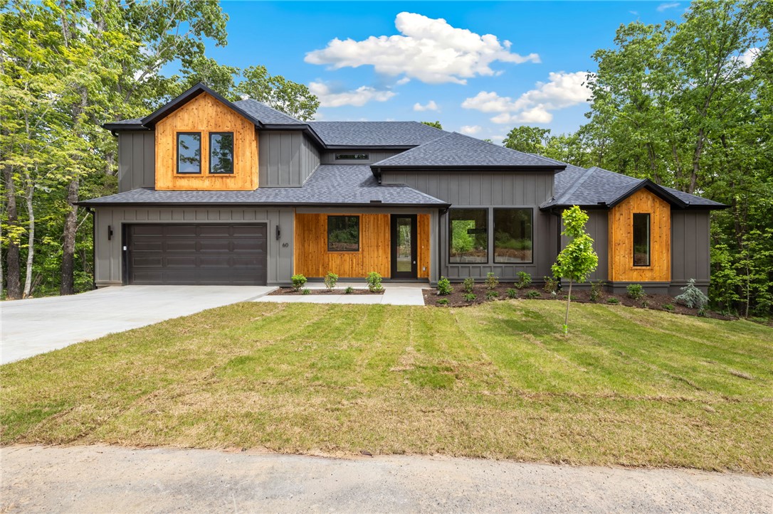 Stunning 3BR, 2-story home with office in Bella Vista near Loch Lomond, blending modern design with warm natural elements. The inviting living room features a striking stone fireplace, expansive windows, and soaring ceilings that fill the space with light. A chef’s kitchen impresses with custom cabinetry, sleek black countertops, large island, designer lighting, and open flow to dining and living areas—perfect for entertaining. The private primary suite offers a serene retreat with spa-like bath, dual vanities, soaking tub, and walk-in shower. Thoughtful details and upscale finishes shine throughout, from wood accents to clean architectural lines. Enjoy peaceful wooded views from the covered deck and a beautifully crafted exterior that stands out. A perfect balance of style, comfort, and location!