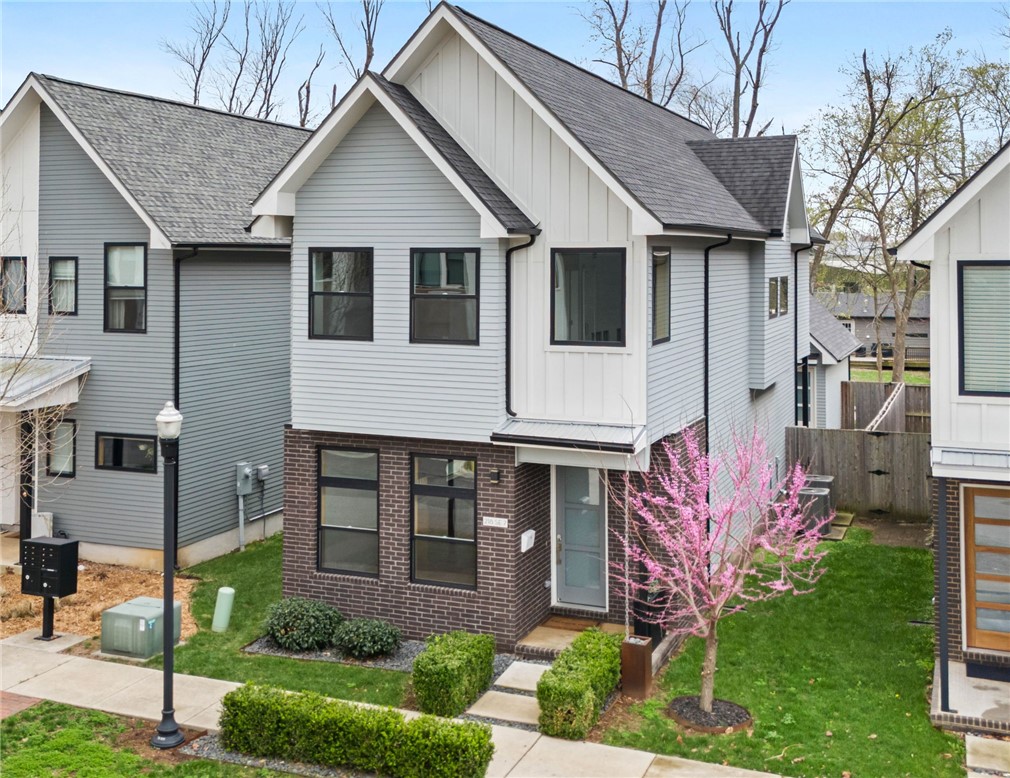 Immaculate and MOVE-IN READY! This modern home offers exceptional downtown Bentonville living in the vibrant Arts & Market District. An abundance of natural light throughout, expansive windows, modern finishes and warm hickory floors create an inviting and sophisticated space. The main level includes: quartz countertops, large island, ceiling-height cabinetry, premium appliances, pantry, coffee/wine bar, dining, 1/2 bath, garage access, nook, storage closet and 2 coat closets. Upstairs, the primary suite offers cathedral ceilings, large windows and a spa-inspired bath with a high-end bathtub and a large walk-in shower. Two spacious bedrooms, a full bath, laundry room, linen closet and a flexible space ideal for a home office make the second floor functional. 2-car garage with ample attic storage. Outdoor living includes a covered composite deck, fenced yard with natural grass and 2 gates.  Located across from Thaden School & minutes from Walmart Home Office, The Momentary, Crystal Bridges & the Bentonville Square.