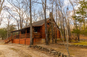 Beautiful one bedroom, one bath log cabin nestled on 2.77 acres. This cabin is complete with open living/dining/kitchen floor plan, plus spacious loft for recreation, office, or additional sleeping space. Interior barn wood and cedar walls highlight the impressive rock gas fireplace. Andersen triple-pane windows, new central heat/ac and 2 backup heat sources guarantee winter comfort. The exterior has fresh stain, new gutters, new roof on back half of house and 600 gallon propane tank.  In addition there is a 20x20 shop building with new roof.This property is Secluded, yet not far off pavement and only 15 minutes from town. Don't miss out on this truly original Ozarks cabin!