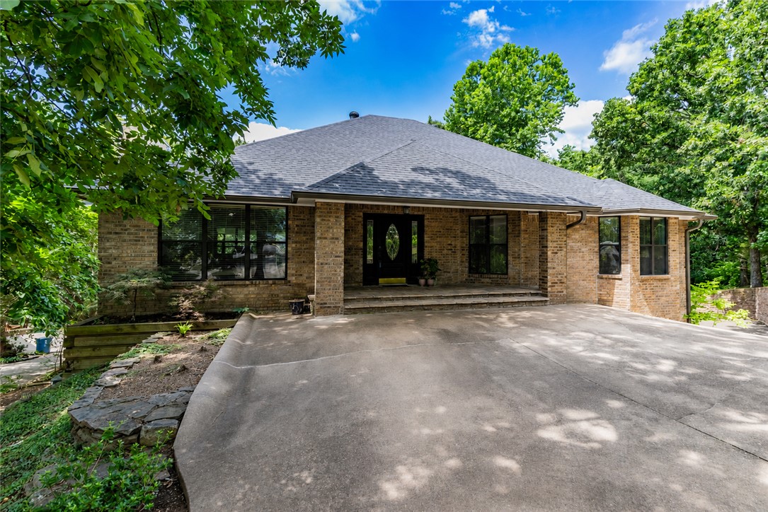 Seasonal views, ACC-approved lake access, and the privacy only Mother Nature can provide - this Loch Lomond-area home is the kind of property that makes you exhale the minute you arrive. With an additional 0.36-acre parcel included, the setting feels tucked away and peaceful while still offering all the perks of Bella Vista living.  Inside, the main level features real hardwood floors, two bedrooms, and one full bath, with windows that pull the natural setting right into the heart of the home. Downstairs, the walk-out basement adds one bedroom, one bath, and a flexible living space ideal for guests, a home office, or recreation.  A covered patio stretching the full length of the home invites year-round enjoyment, while recent improvements - including a newer roof, HVAC, hot water heater, and garage door - bring peace of mind. There’s also an unfinished bonus/rec room off the garage plus a workshop or golf cart storage area, offering the kind of versatility buyers love.