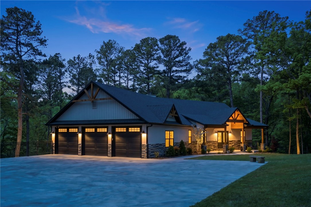 Nestled on 2.39 acres across seven adjoining lots, this custom-built 2022 farmhouse offers rare privacy at the end of a secluded cul-de-sac with its own private street. Thoughtfully designed with a split floor plan, this 3-bedroom home features rich hardwood flooring, oversized windows, and a light-filled interior that seamlessly connects to nature. The chef’s kitchen showcases upgraded KraftMaid cabinetry, premium countertops, and modern finishes. Cozy up by the Pacific Energy wood-burning stove or unwind on the screened-in porch overlooking serene, wooded surroundings. The oversized 3-car garage with epoxy floors and additional under-home storage with roll-up access provides exceptional functionality. Energy-efficient with foam insulation and an 80-gallon water heater. Located near trails, shopping, and Bella Vista amenities—this is a one-of-a-kind retreat blending luxury, comfort, and acreage living. Easy access to Back 40 trails right from the home!