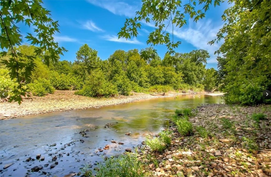Incredible 224-acre estate w/over half a mile (~3500ft) of White River frontage—just outside Fayetteville. Nature lover & sportsman's paradise w/wildlife, two ponds & breathtaking views. The 9,920sf lodge features hand-hewn logs, custom doors, 5 stone fireplaces, stacked stone exterior, geothermal heated floors, metal roof & elevator. Inside: 4 beds, 5 baths, loft & safe room/full separate apartment. Massive 44’ x 36’ great room perfect for entertaining, events, or retreat use. Over 3,800sf of covered porches, balconies & patios. Also on the property are 2 guest homes (~1250sf each, not included in listed square footage) & ~8400sf of detached buildings - a tiny cabin, greenhouse, barns, goat & horse stables, chicken coops, metal buildings & original homestead water well. Fenced & cross-fenced. Potential as private estate, corporate retreat, working farm, or event venue. City water/electric. Built 2002. Exceptional craftsmanship. Sold as-is. Priced below appraisal. Updates & some finishes required. Appointment only.