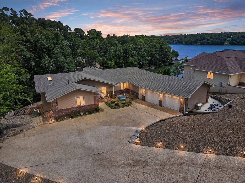 Luxury lakefront living on beautiful Loch Lomond. Nearly 4,000 SF of thoughtfully designed living space showcasing panoramic lake views, soaring ceilings, a dramatic wall of windows, wood burning fireplace, formal dining, wet bar, and sunroom. The main level features a spacious owner's suite, while the walkout lower level offers exceptional flexibility with guest accommodations, a second living area with fireplace, second kitchen, and heated/cooled bonus rooms ideal for a home office, fitness studio, media room, hobby space or overnight guests. Enjoy the large, covered patio overlooking the lake and your private covered dock with boat lift, fishing structure, underwater lighting, and easy water access. Oversized garage, abundant storage, and quality throughout create an exceptional waterfront lifestyle on one of Bella Vista's most desirable lakes.