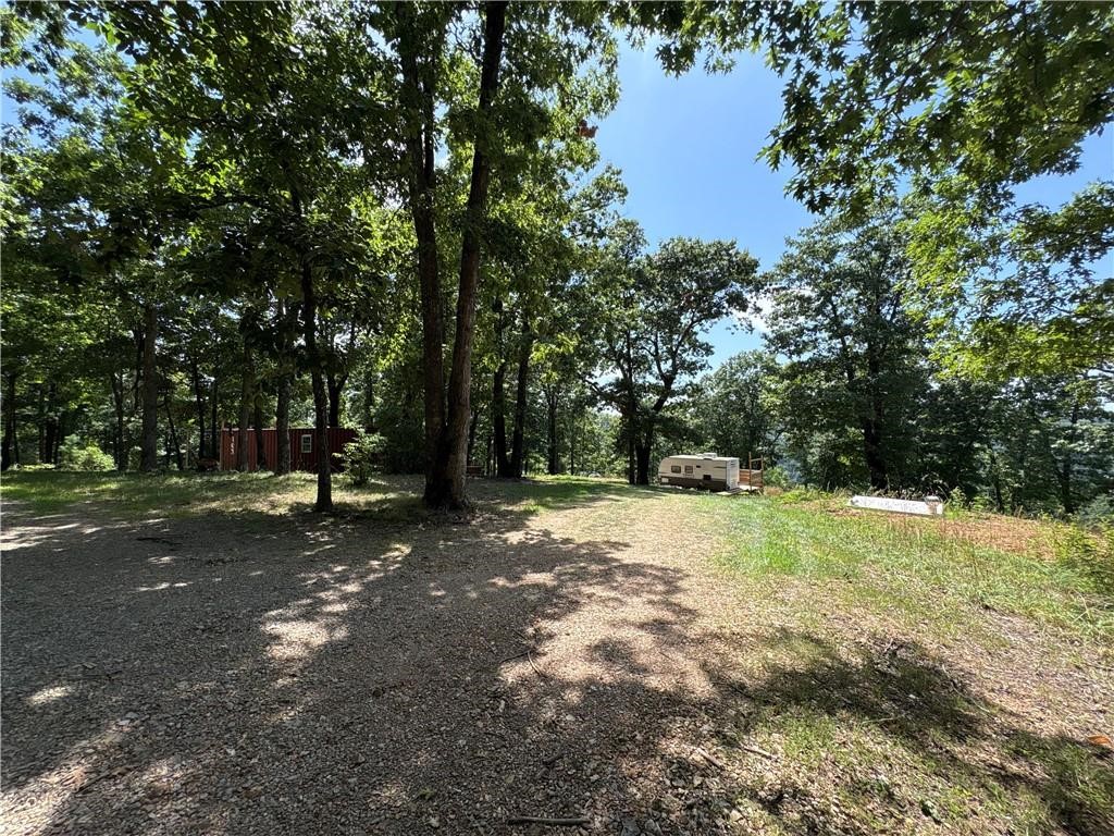 4.9 acres offering privacy close to the end of the road and no restrictions! Property feature electric, rural water, septic, and a new storm shelter (11/2024). Includes a leveled shipping container with door, window, and wood stove. Large pad for camper, multiple potential build sites and a viewing deck overlooking a finger of the Buffalo River Grand Canyon - endless possibilities  for year dream getaway, build, or retreat.