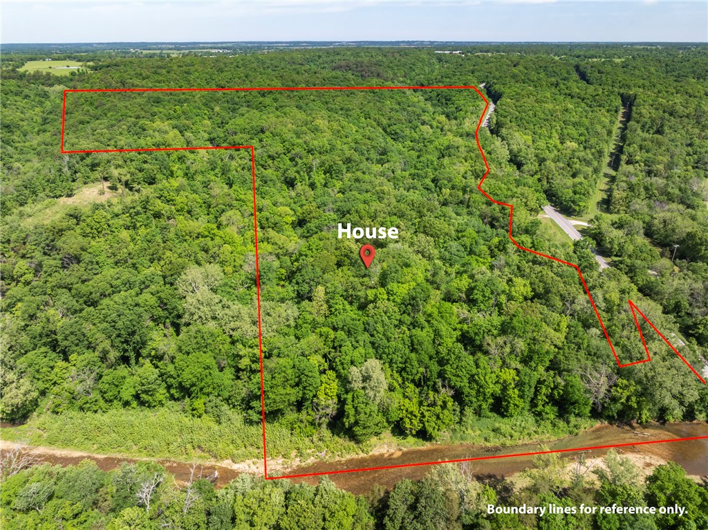 Located across the road from Rootville with frontage on Spavinaw Creek, this rustic, secluded cabin/house was built in the 1970s by the family who have owned this land for generations and the two story insulated metal outbuilding was added later. The 2 BR 2 BA house has electricity, septic, propane and a well on the property. The outbuilding could easily become a barndominium & is insulated with electricity.  The 69.65 acres of pristine woods, 600 plus feet of creek access just below the house sits amid mature woodlands and beautiful low cliffs and rock formations making it perfect for recreational use. This property is located next to a private hunting and fishing recreational facility.   The original concrete block house has a metal roof and is sturdy.  It could be a retreat cabin or become the beginning of an amazing larger home. You will want to see this for yourself. The lines drawn are not a survey but an estimation of property boundaries. House and outbuilding sold as is. Also See MLS# 1344756