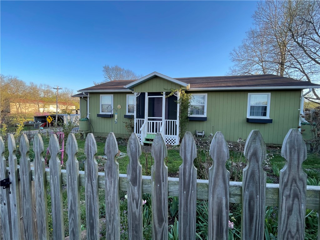 This charming home is within walking distance of the town square and a variety of local restaurants, shops, and grocery stores. The property features a comfortable floor plan with a spacious living area and a large primary bedroom that includes a generous walk-in closet.
The front room can serve as an additional bedroom and includes an armoire that will remain with the home. There is also a small office space, perfect for working from home or a hobby room.
The kitchen is equipped with a gas stove and a newer refrigerator, both of which will stay with the property. The washer and dryer are also included.
Outside, you'll find a newer storage shed and a small greenhouse in the backyard. The yard is beautifully landscaped with perennial flowers and hostas, creating a lovely outdoor space to enjoy throughout the seasons.
Conveniently located, the home offers an easy 30-minute commute to the Northwest Arkansas metro area.