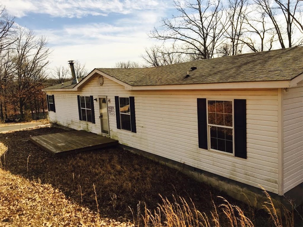 Great Investment opportunity in Bella Vista! Large mobile home with spacious living area. Home features a wood burning fireplace, built-ins and a large deck perfect for entertaining. Wooded view from the deck offers privacy. Bank will finance, call list agent for details. Flooring and paint will be repaired.