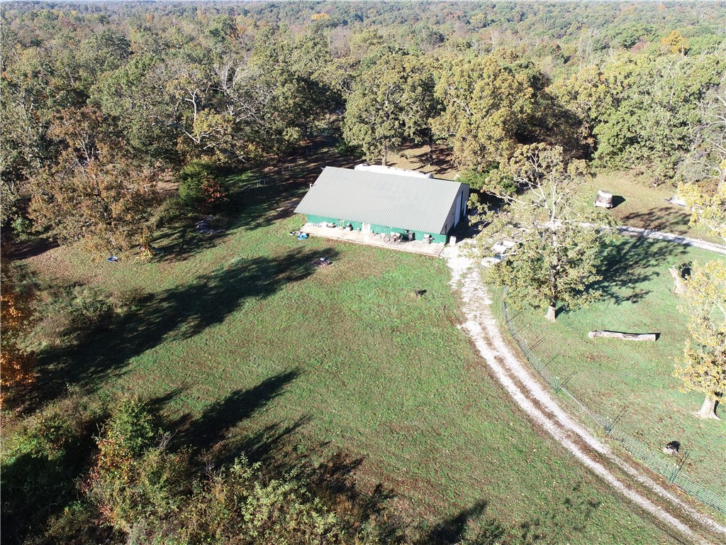 Experience ultimate peace and tranquility just a 35 minute drive from Downtown Bentonville with this rare 20 acre offering. The custom shop features comfortable living quarters seamlessly connected to a large, attached shop, providing ideal utility for projects or storage. Set on 20 acres, the property offers plenty of deer for hunting opportunities and incredible potential for opening up commanding views of the rolling Ozark hills. The expansive land includes multiple homebuilding sites for an additional residence of future development. This unique property combines modern functionality with an expansive, private landscape, perfect for those seeking country living with quick city access.  More property available for purchase up to 60 acres total.  Include more acres in offer if needed.