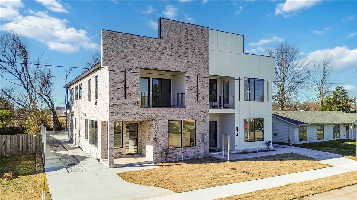 Welcome to effortless modern living in the heart of Bentonville. This newly constructed townhouse showcases exceptional craftsmanship and thoughtful design, offering four spacious bedrooms and 3.5 bathrooms—including two primary suites that provide flexibility for co-living, guests, or multi-generational living. The gourmet kitchen features high-end appliances that will delight any home chef, while an additional kitchenette adds convenience and versatility. The open-concept layout is bathed in natural light from generous windows, creating a warm and inviting atmosphere. Step outside to a large covered patio perfect for relaxing or entertaining, rain or shine. Located within walking distance to 8th Street Market, Thaden School, and the Walmart Home Office Campus, this home places you at the center of Bentonville’s vibrant community. From premium finishes to a smart floor plan, every detail reflects quality and comfort. If you’re seeking space, style, and location, this one checks all the boxes.