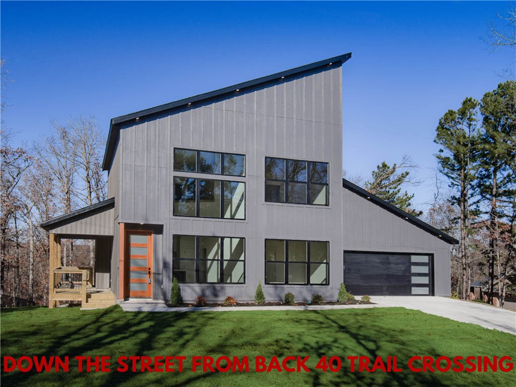 DOWN THE STREET FROM THE BACK 40 TRAIL CROSSING! This modern new construction home sits on a flat .33 acre wooded lot. Provides easy access to Lake Brittnay and Metfield Golf Course. This stunning home showcases modern high-end finishes throughout! 2 bedrooms + office. Step inside to discover beautiful floor-to-ceiling custom cabinets and a huge waterfall island, perfect for entertaining family and friends. The kitchen is also equipped with premium black stainless steel appliances, including a gas range. NO CARPET! Breathtaking two-story living room with huge windows going up to the ceiling! Retreat to the primary suite with high ceilings and a stunning walk-in tile shower that elevates your everyday routine. Guest bedroom is located on main level. Bentonville schools! As a bonus, the buyer can receive $3,500 in closing costs when using the builder's preferred lender. Schedule your showing today!