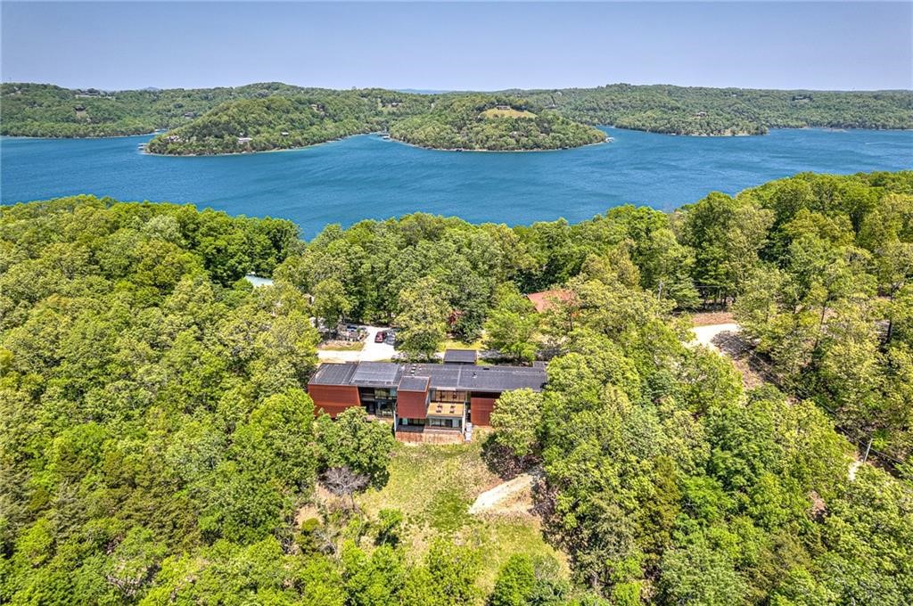CUSTOM BUILT AND DESIGNED CONTEMPORARY MASTERPIECE TUCKED AWAY ON A 1.48 ACRE PARTIALLY WOODED LOT BOASTING SPECTACULAR OPEN VIEWS OF BEAVER LAKE! One slip in the community boat dock nearby! Private pool room w/ indoor heated swim spa, hot tub & bath!  This unique property was built & designed to be energy efficient and low maintenance with a metal exterior and floor to ceiling commercial grade windows and sliders throughout that fill this work of art with natural light and bring the outdoors inside! The main level hosts a sleek & functional chef’s kitchen, formal dining, media room/study w/ built-ins, screened deck w/ outdoor kitchen, a living area w/ dual sided fireplace, built-ins w/ wet bar & an exceptional lake view!  Main level primary suite also enjoys floor to ceiling windows w/ amazing views and a luxurious en suite bath w/ walk-in closet! Lower level features 2 bedrooms each w/ a private en suite bath, large unfinished bonus/hobby room/4th bedroom. Fabulous outdoor living spaces! Large workshop w/ view!