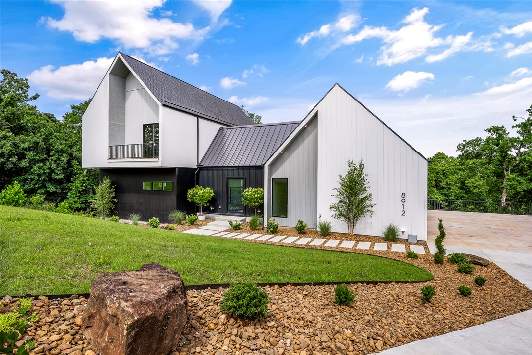 Welcome to The Hollows at Beaver Lake, a luxury gated estate community where modern architecture, privacy, and outdoor living come together in one of Northwest Arkansas’ most distinctive settings. Featured in the Northwest Arkansas Parade of Homes, this custom residence offers three levels of thoughtfully designed living space with soaring ceilings, dramatic walls of glass, and a stunning floating staircase. Designed for entertaining, the home features 4 bedrooms, 4.5 baths, expansive decks and covered balconies, plus a private spa courtyard complete with a premium hot tub and custom steel-and-timber pergola. Situated on 1.28 acres in a gated luxury community near Beaver Lake. Enjoy convenient access to Prairie Creek Marina, downtown Rogers, Bentonville, and the Walmart corridor. A rare opportunity to own a truly exceptional modern retreat.