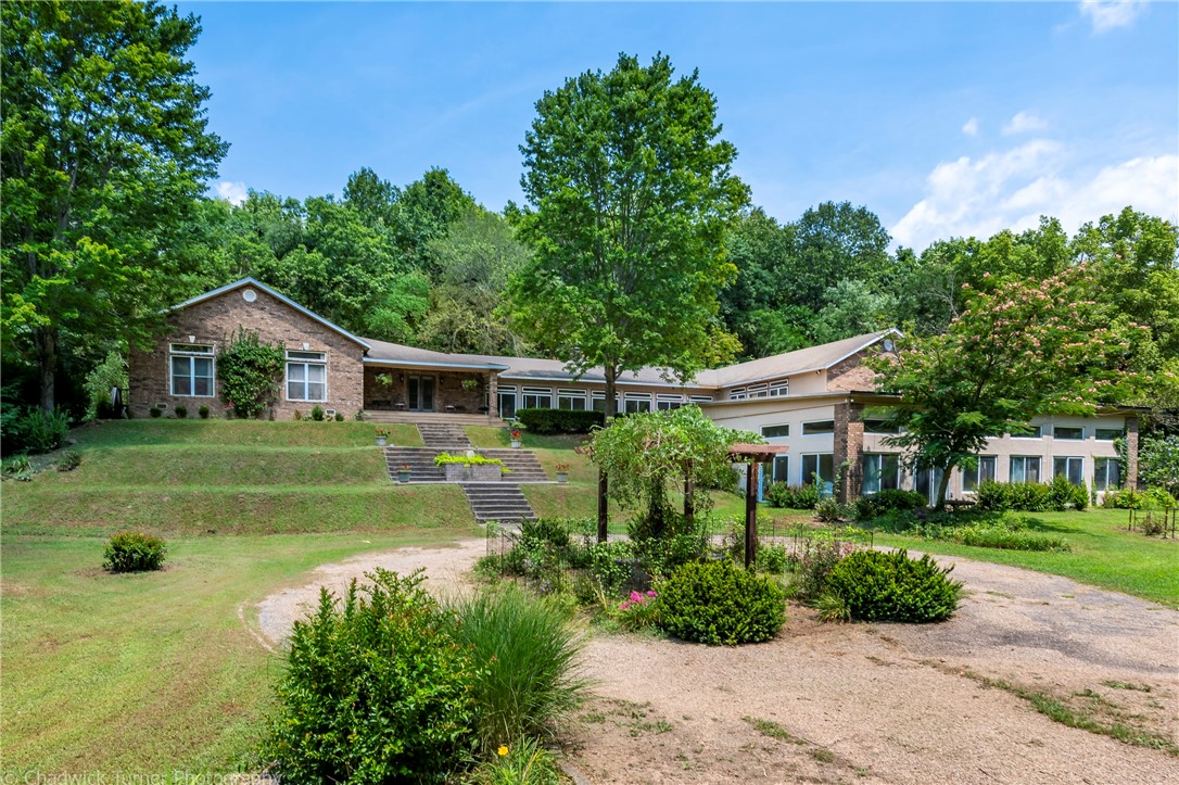 Well maintained, much loved & relished home on 17.52 ac in Bentonville is beyond compare! It provides desirable privacy, natural beauty, loads of storage & a time-honored 100 year old barn! This property would make an amazing place to raise a family or a wonderful investment Airbnb. The home is 400 ft from mountain bike trails-Back Forty loop for biking enthusiasts (attached map) & only 15 min to Downtown Bentonville. The home itself provides great options for entertaining or plenty of space for a family to spread out. Featuring an extensive kitchen with 4 sinks, 2 cooktops (1 electric & 1 gas) & loads of storage in custom designed cabinets. Gorgeous formal dining & living rooms, 2 large family rooms, a sunroom, 3 bedrooms with en-suite bathrooms, providing that desire for additional privacy. Head downstairs to an indoor pool for a swim during any season! Don't miss, 2 courtyards for moments of peaceful relaxation & refreshment OR hunting potential with abundant wildlife. Big Green House perfect the gardener in you