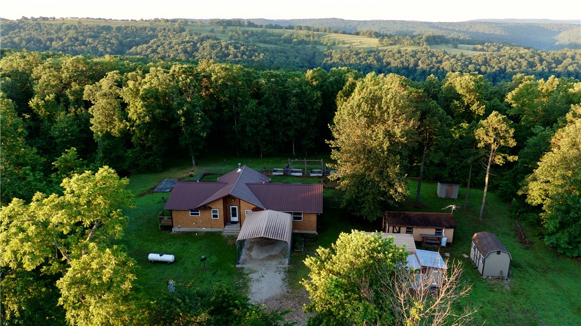 Peaceful 35± acre homestead bordering the Ozark National Forest with direct access to thousands of acres of public land. This 1,578 sq-ft 2BR/2BA home features a spacious living area with large windows, LVP flooring, and a wood-burning stove for supplemental heat. The kitchen offers wood cabinetry, granite countertops, and a propane cooktop and oven. Sliding doors from the dining area and primary bedroom lead to a composite deck overlooking the fenced backyard. The home is supplied by a rainwater collection system with 5,000 gallons of storage. Multiple outbuildings provide storage, workshop, studio, or guest space potential. The property features mature timber, gentle terrain, nearly a mile of trails, abundant wildlife, wild blackberry bushes, a stocked pond, and several potential building sites. Located south of the Buffalo and Little Buffalo Rivers and only 25 minutes from Jasper, this property is ideal for a homestead, hunting retreat, or outdoor getaway.