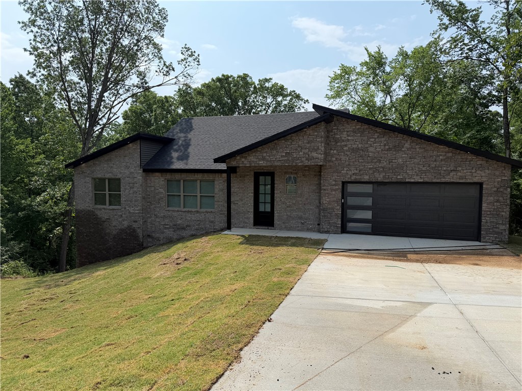 Beautiful new construction 3BR/2BA home nestled among the trees in Bella Vista, offering modern finishes, an open layout, and peaceful wooded views. The bright living area features vaulted ceilings, abundant natural light, a sleek electric fireplace, and durable wood-look flooring throughout the main spaces. The kitchen is designed for entertaining with quartz countertops, custom cabinetry, stainless steel appliances, large island, and walk-in pantry. Spacious primary suite includes a spa-like bath with double vanity, soaking tub, tiled walk-in shower, and oversized walk-in closet with built-ins. Covered back deck overlooks the private wooded setting, perfect for relaxing outdoors. Additional highlights include stylish secondary bath finishes, dedicated laundry room, and quality craftsmanship throughout. Conveniently located near Bella Vista trails, golf, lakes, and amenities with easy access to Bentonville.