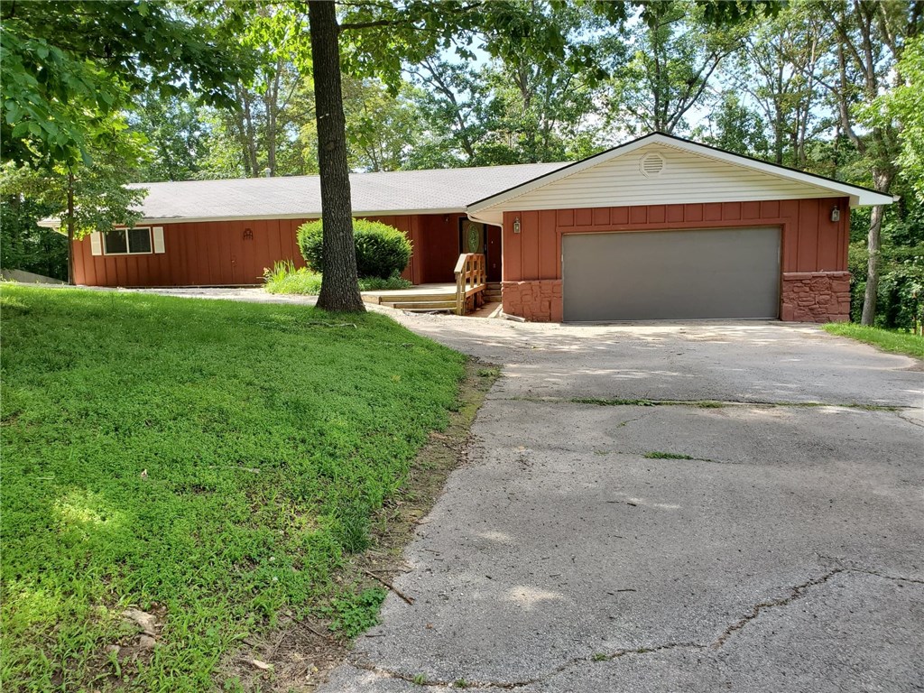 Country setting on this 1+ acre corner lot in Little Flock. 3 Bedrooms/2 Full Baths & very open living area concept. Gourmet kitchen w/granite counters, double oven, gas cook top in center island, refrigerator & dishwasher offer great views to living room w/wood burning fireplace & dining/sun room. Hardwood floors in open area. Sun porch, screen porch & lots of deck for entertaining. Master Bath has jetted tub & walk in shower. 2 Car garage & circle driveway.  Lawn care is provided by owner.