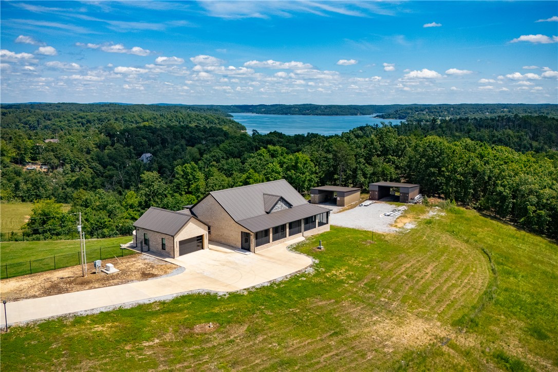 Live your legacy on 40+ acre estate on Beaver Lake, complete w/2 homes w/the opportunity for a 3rd. The ~12Ksqft all brick barndo features soaring ceilings, grand htd/cld entry, walkout rooftop terrace, outdoor kitchen, sunroom, office, flex space, 2nd living room, laundry on each level, & 5BR/7.5BA. Enjoy ~4000sqft htd/cld shop w/220V outlets, 6 air compressors, & custom garage doors. The finished ~2700sqft guest home offers 3BR/2.5BA, custom built ins, office, chef inspired kitchen w/tall cabinetry & waterfall countertops, hidden storage throughout, glass corridor, & screened in porch surrounded by breathtaking views. This estate includes buried propane tanks, RV sites w/utlities, htd/cld well house, conexes, & a community boat slip. The private gated estate causeway, poured concrete, brick rentention walls, and peaceful lakefront setting make this ideal for a compound, homestead, event venue, or private escape from the everyday hustle. Luxury, Privacy, & Potential.