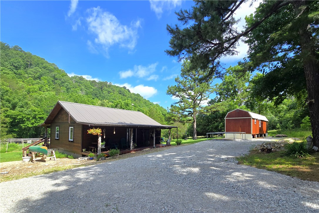 Homesteader's dream on 12 acres with income potential! This thoughtfully designed one-bedroom cabin features outstanding craftsmanship, blue pine floors, custom cabinetry, beautiful finishes, and creative space-saving design throughout. The property offers maintained (named) hiking trails, 1250 ft. spring-fed creek frontage, a 3500 sq.ft. fenced garden area, worm beds for nightcrawler production, and certified wildlife sanctuary status through the National Wildlife Federation. A separate utility building houses the washer/dryer, Culligan system, water pump, and sauna. There is also an additional outdoor shower and outdoor kitchen on the front porch with propane grill. A tiny house is currently under construction, with ample room for additional cabins. Additional features include a well-organized workshop space, buried electric, water well, electric and wood heat. According to FEMA maps, the home and all structures are outside the flood zone. No covenants or restrictions. Private, yet conveniently accessible.