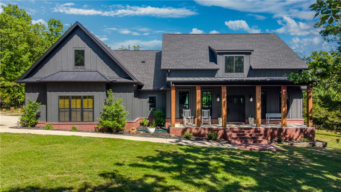 Y'all, this one stopped me in my tracks. Tucked away on 6 gorgeous acres just outside West Fork, this 2022 farmhouse is everything I love — brick and board-and-batten, massive Douglas fir porch posts, and a covered back deck overlooking the most beautiful mature hardwoods. It feels like a sanctuary the moment you pull up. Inside, the split floor plan flows just right, with LVP floors, a cozy electric fireplace, and finishes that are thoughtful and intentional throughout. The jack-and-jill bath for the guest rooms? Beautifully tiled. The primary suite? A true retreat. Upstairs, a bonus room gives you that extra space every family needs. And outside — oh, the outside. A greenhouse, raised garden beds, seasonal streams, and game trails winding through the trees. Plus a 30x50 shop with 100-amp service for all the projects ahead. A concrete safe room adds peace of mind without sacrificing an ounce of charm. Twenty minutes to Fayetteville, but feels like a world away. This is the one, friends.