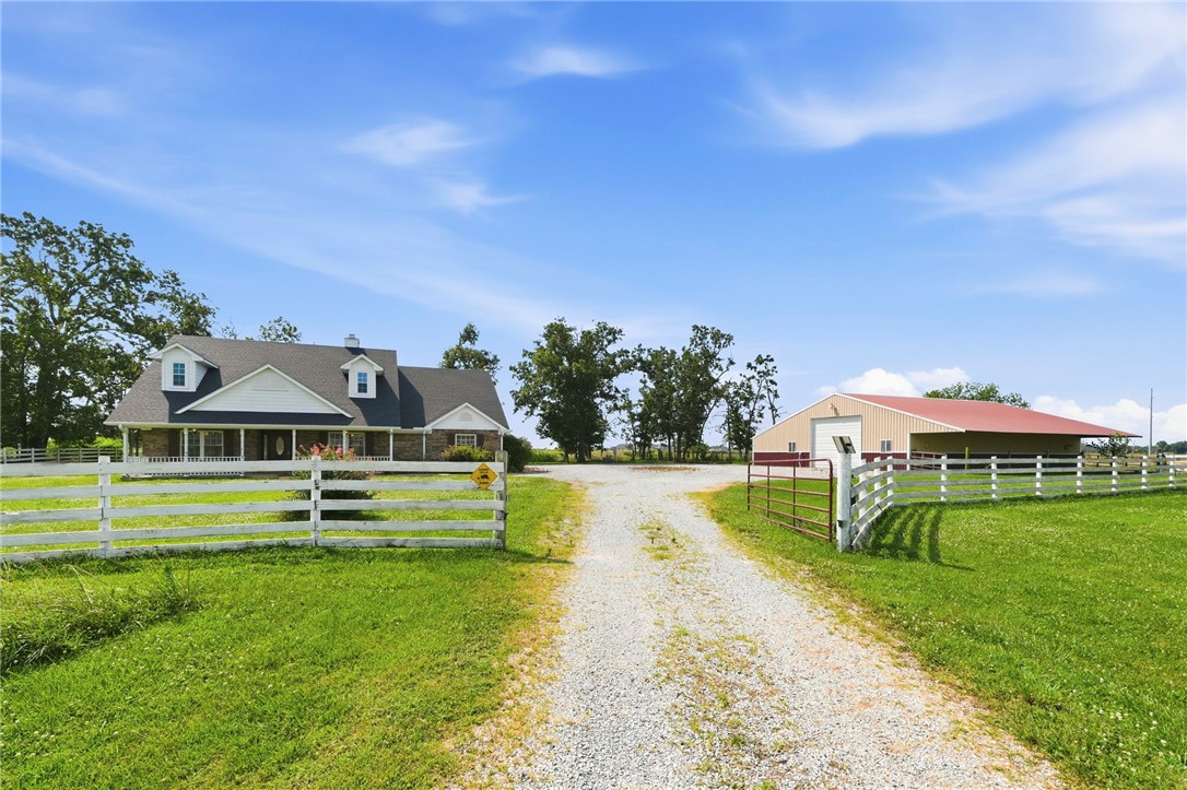 Rare 5.94 acres directly in Centerton's path of growth. Set well back from the road behind a fenced, gated entrance, this one-level 3BR/2BA home sits under mature hardwoods with open pasture around it - real privacy, minutes from town. The 3,660 SF shop is the headline: clear-span steel frame, concrete floor, oversized overhead door, power and lighting, plus 1,260 SF of covered lean-to. Inside: a vaulted great room with floor-to-ceiling stone fireplace, granite kitchen with breakfast bar, and a primary suite with garden tub and oversized walk-in closet.