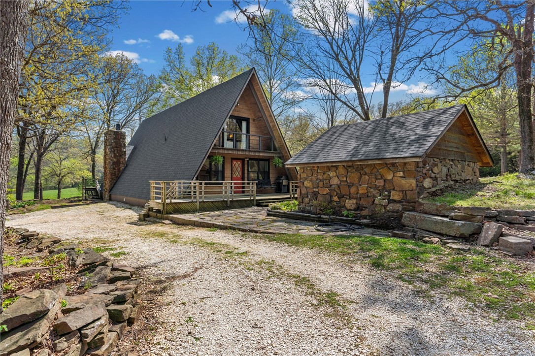Whether you are looking for a permanent home or a weekend retreat, this property has a lot to offer. Surrounded on three sides by rolling hills and natural forest, the peaceful valley setting is beautiful in all seasons, but stunning in the fall. Minutes from Historic Canehill, the remodeled A-frame home sits just down a well-maintained gravel road with easy access from Fayetteville, Ft. Smith, or Siloam Springs. Nice mixture of woods and open fields along with a pond and wet weather creek. ATV trails run throughout the property. The end-of-the-road location offers privacy, seclusion, and peace. The charming cabin has been completely remodeled but retains the 1970s charm with its vaulted ceilings, wall of windows, stone fireplace, and original pine floors. Don’t miss the recent (2025) barn conversion with its additional bath, full kitchen, and extra storage. There is City water and a well that is plumbed to supply the A-frame, guesthouse, and gardens. Additional acreage available see MLS 1345513