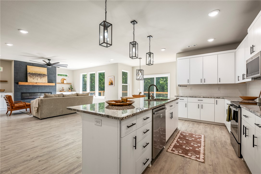 Rare opportunity, up to $10k toward buyer closing costs/rate buy down with acceptable offer helping create a lower monthly payment opportunity. Built in 2023, this light-filled contemporary home offers modern construction in a private wooded setting without the wait. Located on a quiet street in Bella Vista with no homes behind, it provides a peaceful, secluded feel. Inside, expansive windows bring in natural light and showcase the surrounding greenery. The open layout is ideal for everyday living and entertaining, featuring granite countertops, a large center island, walk-in pantry, and sleek electric fireplace. The primary suite includes a soaking tub, tiled walk-in shower, and spacious walk-in closet. A dedicated office or study adds flexibility. Enjoy the generous backyard and elevated cedar-post deck overlooking the trees. Just a short walk to Highlands Golf Course with easy access to I-49. Recent upgrades include fencing, LeafFilter gutters, custom mantel, floating shelves, keyless entry, and privacy shades.