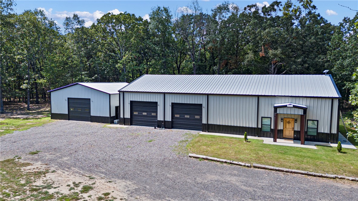 This custom barndominium property offers a highly functional, unique ownership opportunity. Refinement characterizes the interior living space, which adds up to approximately 1,222 square feet. The substantial, insulated shop space provides a scale of utility rarely available. The primary structure's bay is ventilated by fan, attaches to the living space, and totals approximately 2,243 square feet. From here, a heated & cooled bedroom is accessible up a staircase. Electric service is extended to the secondary structure, which is also insulated and totals approximately 1,120 square feet. Storage capacity is further increased with a light building in the back yard. Wooded coverage provides a layer of seclusion, and the portion of acreage with frontage on AR-363 can give way to further development or investment possibilities. Simultaneously, both recreational and business pursuits can be facilitated by this purpose-built property.