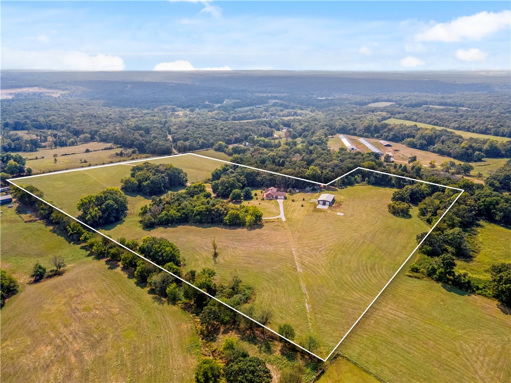 Have you been searching for the perfect place to spread out and call your own? This stunning 27 ± acre mini ranch delivers it all! Nearly 4,000 sq ft of custom living space is designed to impress at every turn. Inside, soaring cathedral ceilings and floor-to-ceiling windows flood the living room with natural light and showcase countryside views. The main level offers the primary suite plus an additional bedroom, while the lower level is its own retreat—featuring two more bedrooms, a game room, a second living area with fireplace, and a full kitchenette with island and dining space. Perfect for entertaining, multi-generational living, or hosting guests with ease.The 40x60 insulated shop is a true standout, with three garage doors, an office, full bath, and laundry. Whether you dream of a hobby farm, recreation, or the peace of country living, this property delivers. Bonus: the home next door is also available, offering a rare chance to live beside family, friends, or create your own multi-property estate.