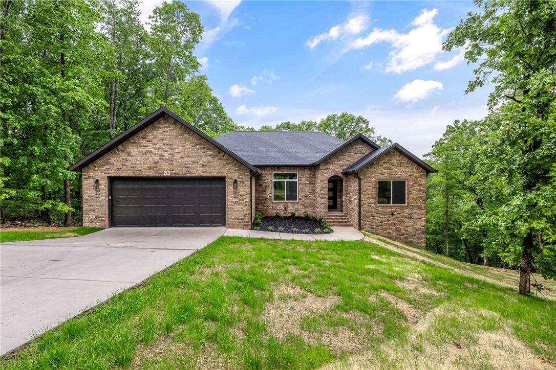 New construction on a beautiful double lot in the southwest area of Bella Vista! Situated on approximately 0.59 acres with peaceful wooded views, this property is conveniently located near Lake Windsor, Tunnel Vision bike trail, and Little Sugar Trails parking. This thoughtfully designed single-level home features an open-concept layout with 11’ ceilings in the main living area, stacked-stone vent-free fireplace, walk-in pantry, and large L-shaped kitchen open to the living and dining areas. Upgraded soft-close cabinetry throughout adds a custom feel. Split floor plan includes 3 bedrooms, 2 bathrooms, office, and oversized 2-car garage. Insulated garage and garage door are desirable upgrades adding efficiency. Private primary suite offers large walk-in closet, dual vanities, tiled shower with dual shower heads, linen closet, and separate toilet room. Enjoy the peaceful wooded setting from the covered back deck, plus the added convenience of LeafShield gutter guards for low-maintenance exterior care.