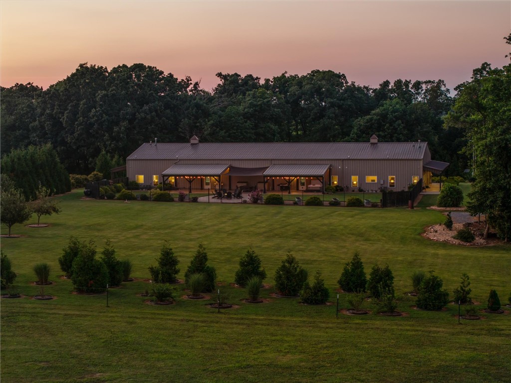 Luxury, versatility, & commercial-grade construction come together in this exceptional Barndominium! Built with durable commercial red iron framing, this one-of-a-kind property is designed to last. Offering 3,756 sqft of living space, it features a 2,350 sqft main residence plus a 1,406 sqft ADU, perfect for multigenerational living, guests, or rental income. Quality finishes include granite countertops & windowsills in the kitchens & bathrooms, along with cultured marble shower surrounds. A tree-lined drive provides privacy and a peaceful setting while keeping you just minutes from town, shopping, and everyday conveniences. With no POA restrictions, you'll enjoy added flexibility. The 2,900 sq ft oversized shop easily accommodates multiple vehicles, and the center bay is RV-ready with an in-floor sewer hookup, 30-amp electrical service, and water access. Built for peace of mind, the siding and structure are rated for winds up to 120 mph, and an in-ground storm shelter in the garage provides added protection.