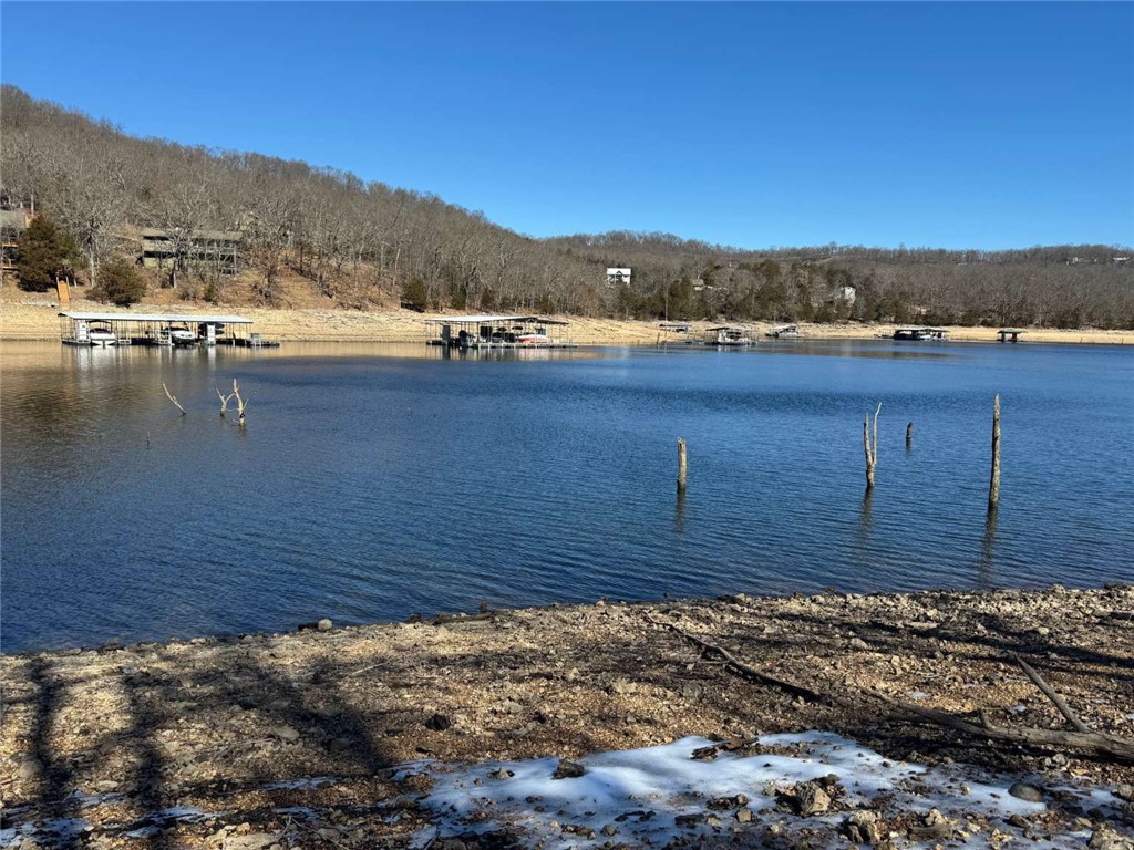 Beaver Lake Land with Private 30' x 20' Dock (Modification approved for 30' x 30' dock). Amazing lake views with 470' of shoreline. A 5 bedroom septic system has been installed. Public water and power are installed on the property. Preliminary site work is done with trees cleared and milled and a large building site graded. A custom home construction plan is available. 5-bedroom home; designed specifically for the Lake Front property: 5139 SQFT Under Roof (5 Bedroom, 4 Bath, 3 Car Garage 3631 SQFT Living (2012 Main Level, 1619 Terrace Level) 232 SQFT Unfinished 834 SQFT 3-Car Garage 108 SQFT Covered Front Porch 280 SQFT Covered Rear Porch Property Features: New 5 BR Septic Installation, June 20, 2025. Includes primary drain field, holding tanks, and required pumps and plumbing. 30 x 20Ft Boat Dock with single slip and swim deck. Approved dock modification and path to the dock by COE. Over 5,000 board feet of lumber milled from the property is available for building a pavilion, greenhouse, or shed.