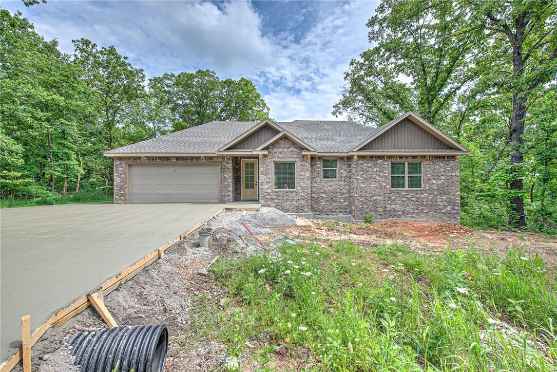 New construction in beautiful Bella Vista! This thoughtfully designed 2-bedroom, 2-bath home offers comfortable, low-maintenance living on a desirable flat lot. The open-concept floor plan features vaulted ceilings, abundant natural light, and durable luxury vinyl plank flooring throughout the main living areas. The stylish kitchen includes white shaker cabinetry, solid surface countertops, stainless steel appliances, and a spacious dining area perfect for everyday living and entertaining. The private primary suite features a walk-in closet and ensuite bath with a custom tile shower. A second bedroom and full bath provide flexibility for guests or a home office. Enjoy peaceful wooded views from the covered back deck. Additional highlights include a 2-car garage, energy-efficient construction, and quality finishes throughout. Conveniently located near Bella Vista's lakes, golf courses, trails, parks, and all Northwest Arkansas amenities.