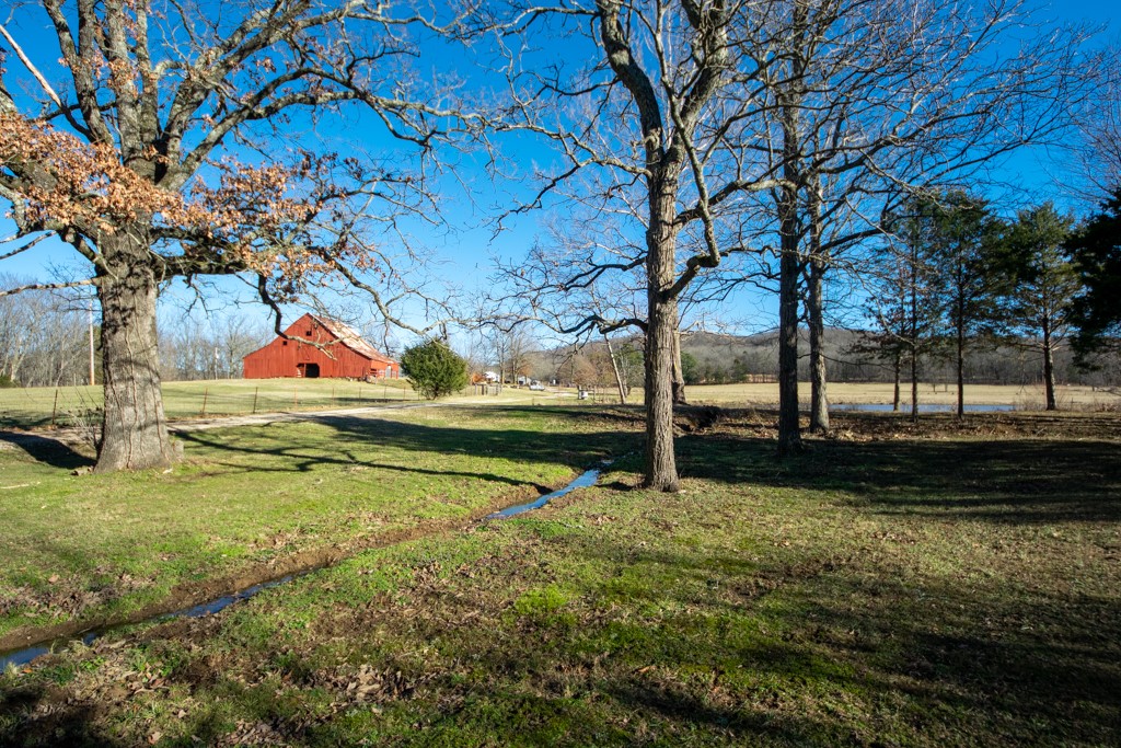 Nestled on this 250-acre paradise is a Vintage farmhouse that boasts five bedrooms, three full bathrooms, two fireplaces, and a magnificent stained deck overlooking The Ozarks. Although the farmhouse is updated, the original charm still exists.  This home includes new wood flooring, custom concrete floors in the kitchen and entryway, new stain-resistant carpet in the bedrooms, and new appliances.  The windows have a lifetime guarantee, the metal roof has a 50-year warranty, and many other unique features you must see.  The stately barn with its fresh, bright red paint surrounded by emerald grass built around 1939 resembles a painting. This 250-acre piece of paradise has pastureland and lush woods, six stocked ponds, natural springs, a waterfall, hiking trails, and a plenty of wildlife. This property offers plenty of room for horses, cattle, goats, or other animals. In addition, a 30x40 shop.  You won't want to leave! see 1193833,1193844,1193845