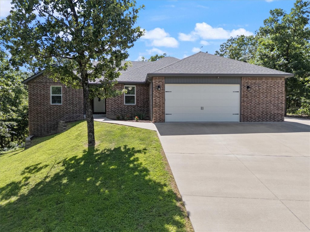 Every trip home begins with a view of Lake Brittany. Tucked away on a quiet cul-de-sac, this 4-bedroom, 2-bath home sits on a beautifully wooded .41-acre sewered lot and features an oversized garage with an extra-wide, extended driveway providing abundant parking for family and guests. Fresh interior paint, new carpet in the bedrooms, and plantation shutters throughout make this home move-in ready. The lush setting feels tucked away while keeping recreation, golf, and everyday conveniences just minutes away. Metfield Recreation Center, two golf courses, world-class mountain biking trails, and the new OZ Bike Park with lift-served riding are all nearby. Whether you're searching for a full-time residence or a weekend retreat, you'll love the combination of seasonal scenic lake views, a peaceful setting, and easy access to everything that makes Bella Vista such a special place to call home.